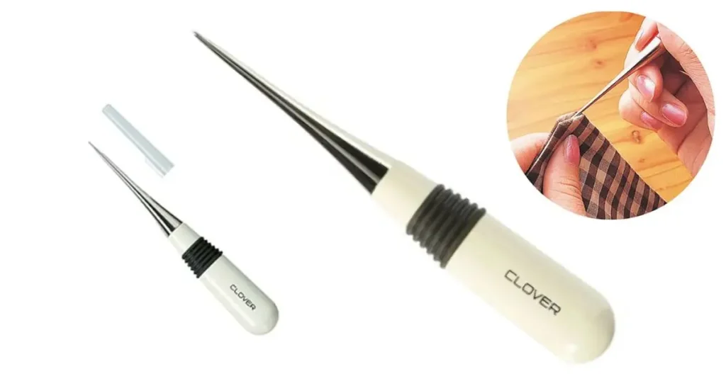 A white and black handled Clover Tapered Awl with a sharp, slender point, shown close-up and in use piercing plaid fabric, ideal for sewing and quilting.