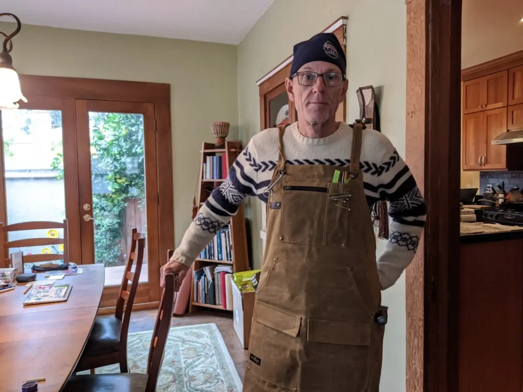 Person wearing a brown woodworking apron indoors.