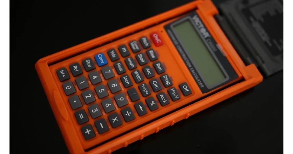 An orange Victor C6000 Advanced Construction Calculator, partially open with its black protective cover, resting on a black surface.
